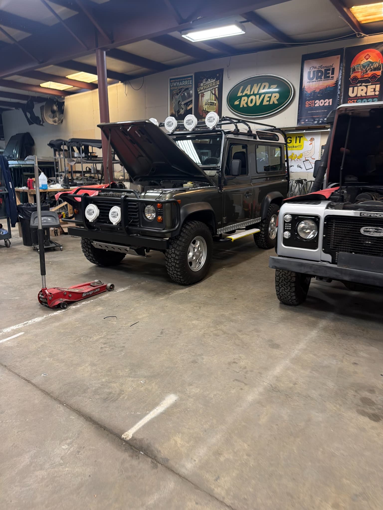 Two Land Rovers with open bonnets inside the LRC workshop